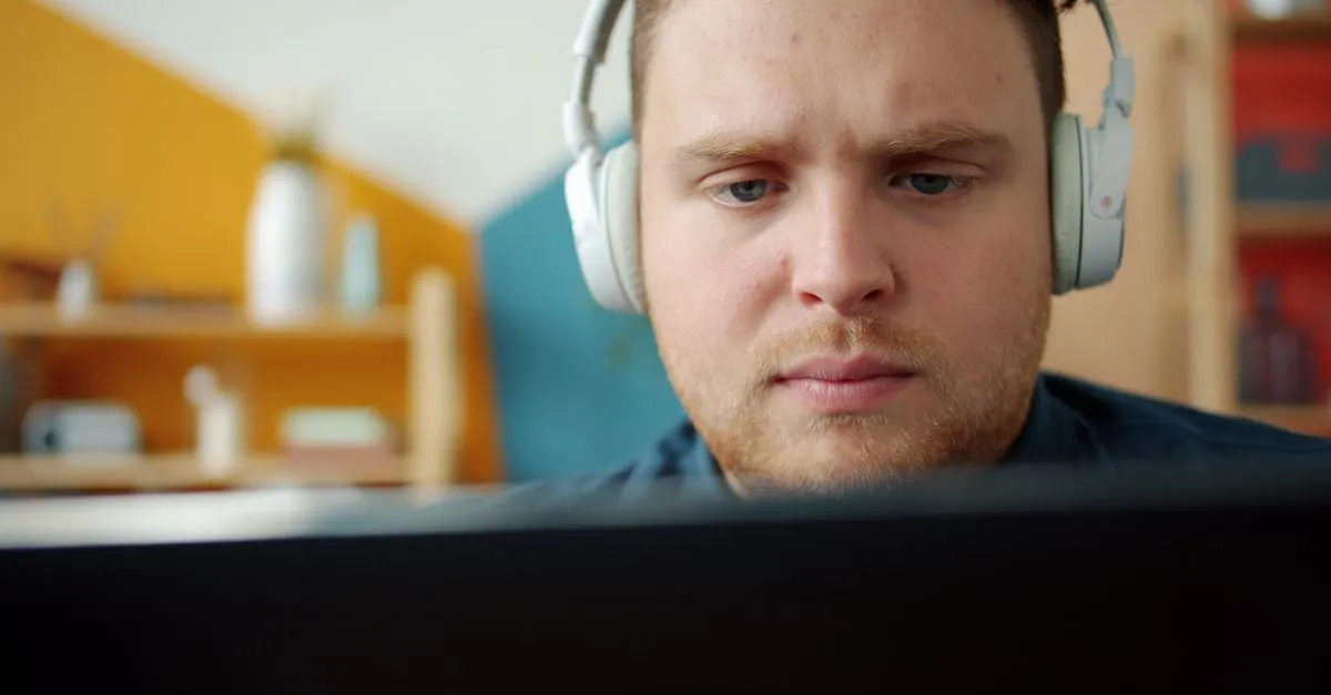Professional wearing headphones focused on transcribing videos on a tablet in a modern workspace.