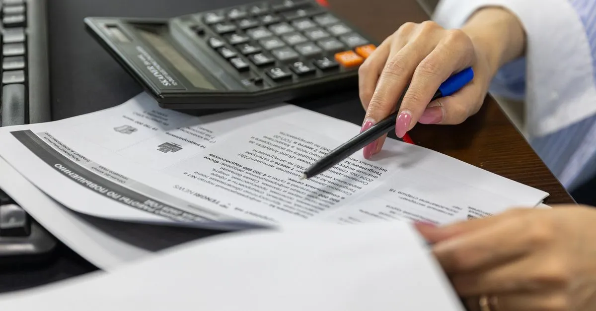 Mãos organizam contas e documentos financeiros, simbolizando gestão de orçamento e reorganização financeira empresarial.