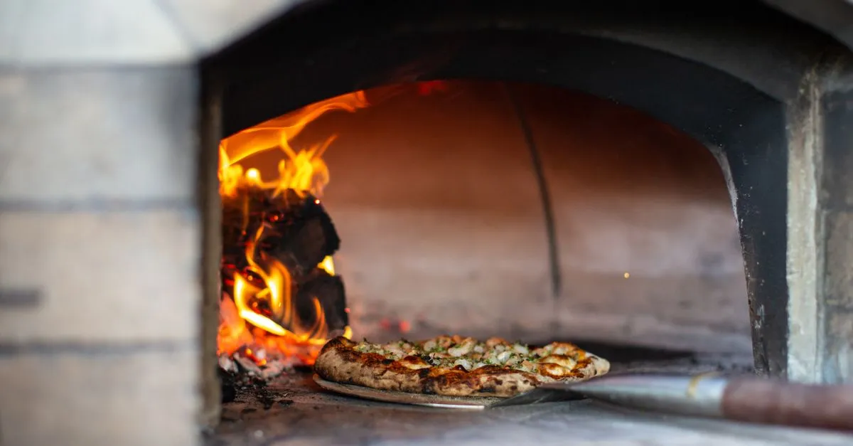 Convidados se servindo em buffet de rodízio de pizza para eventos com forno profissional assando na hora.