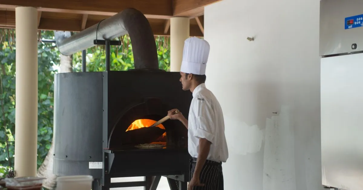 Chef Nonno Eugenio assando pizzas frescas em forno portátil para uma festa em casa com pizza, garantindo sabor único.
