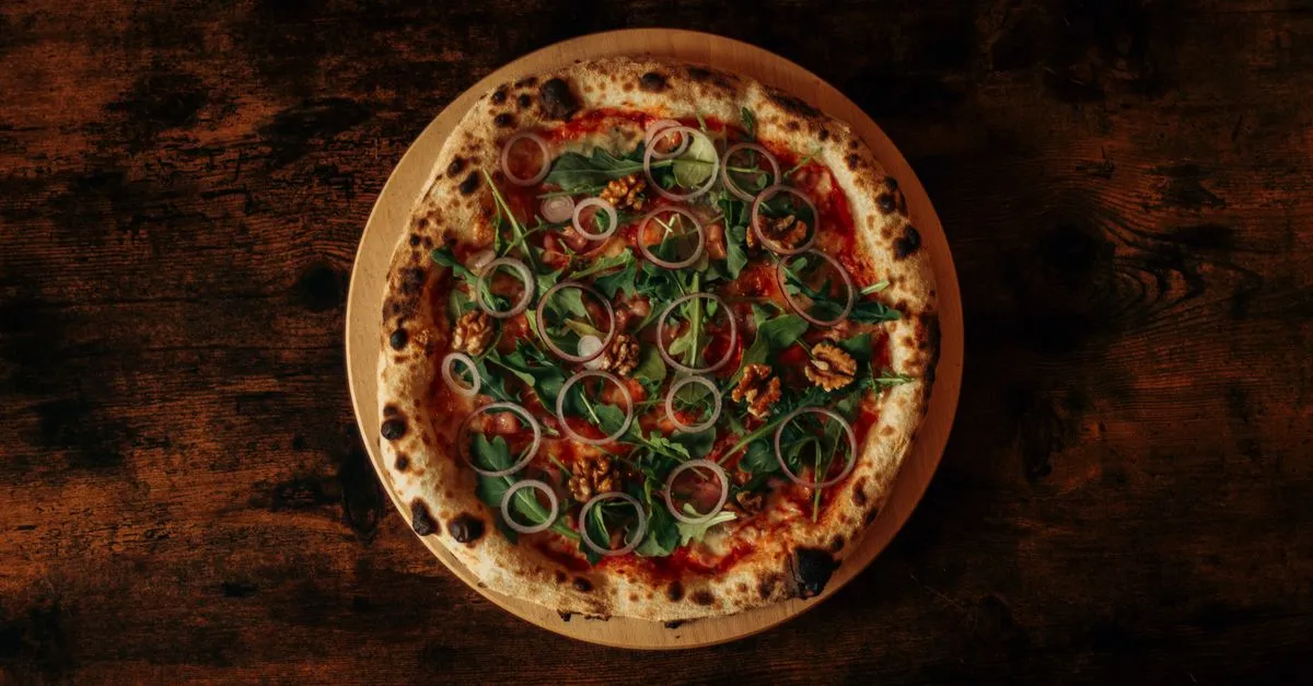 Pizzaiolo experiente tirando pizza artesanal de forno portátil, destacando crosta alveolada e frescor para buffet de pizza para casamento.
