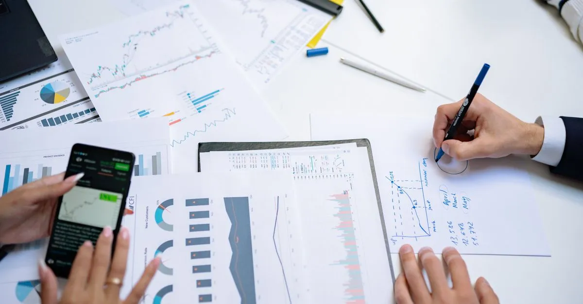 Mãos analisando documentos financeiros e imóveis comerciais, focando no financiamento de imóvel comercial alugado.