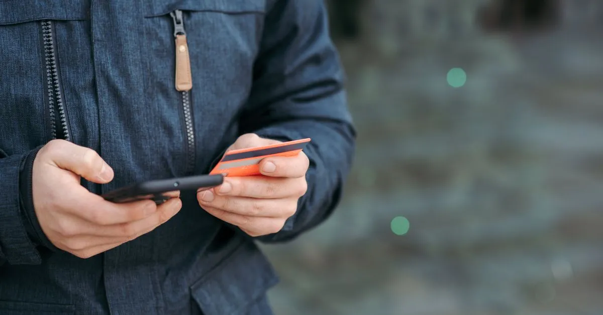 Mão segurando celular com app de indicação, mostrando como ganhar dinheiro indicando crédito sem esforço.