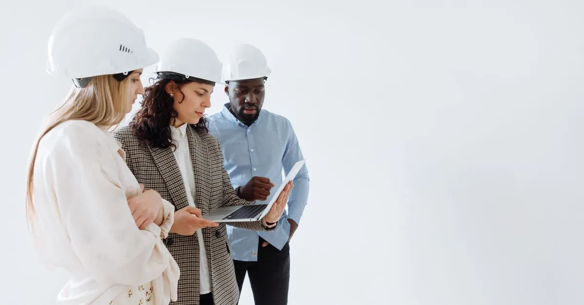 Profissionais e casal em reunião, analisando plantas e projeções para financiamento de imóvel em construção.