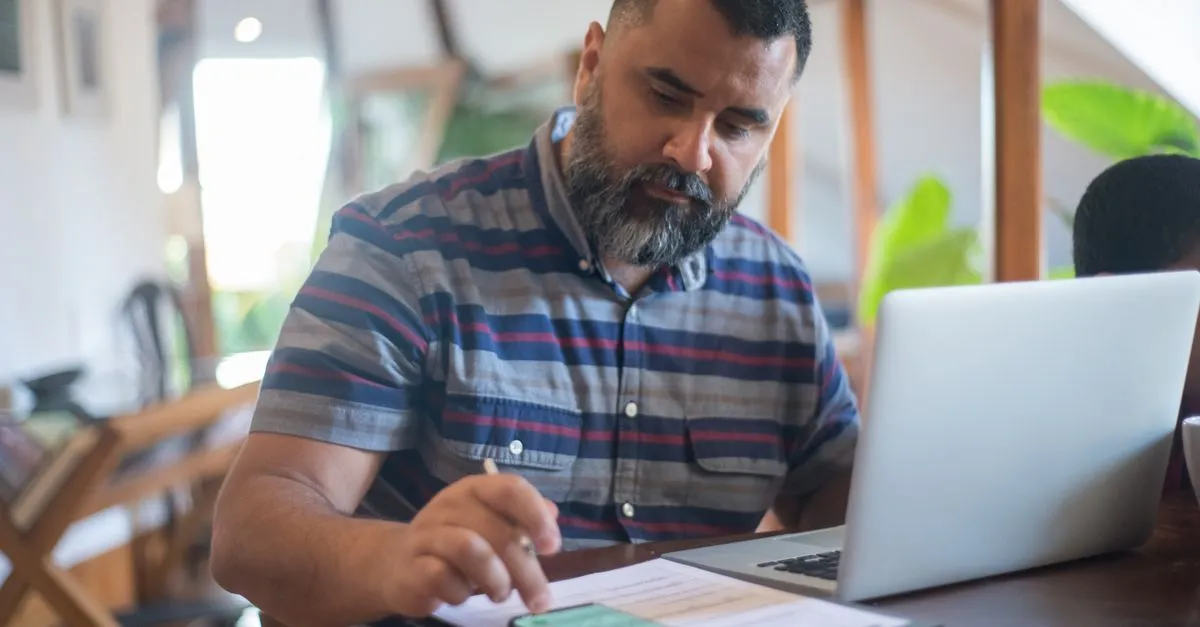 Homem analisando propostas de home equity para quitar dividas com juros menores no computador.