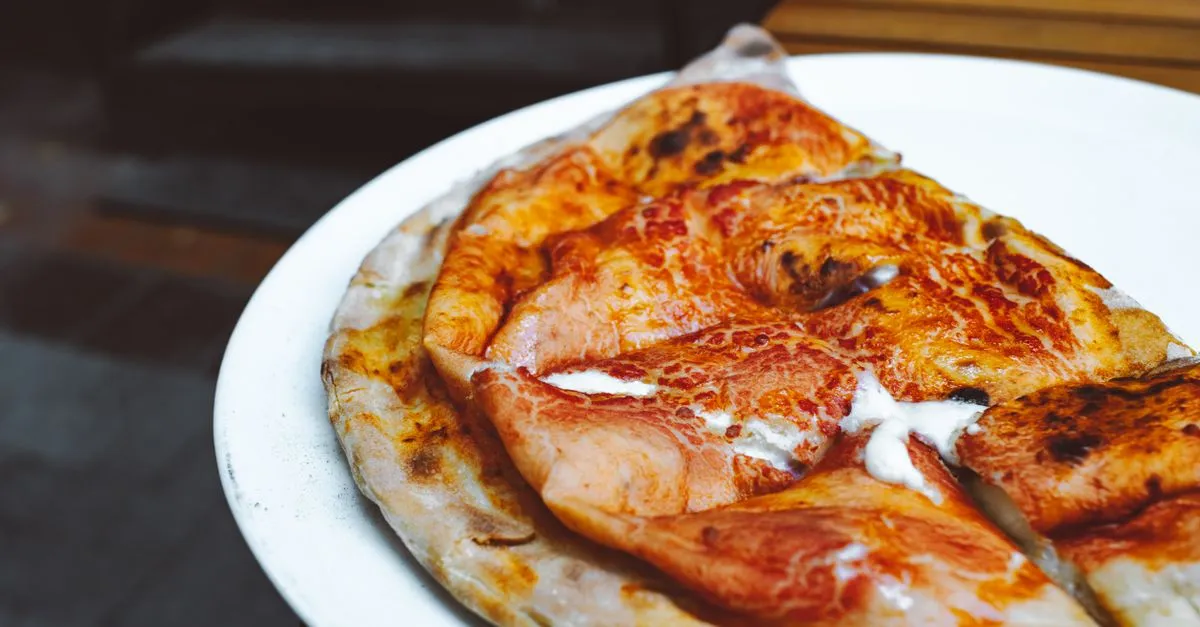 Close-up de pizza napolitana recém-assada, com borda alveolada e crocante, perfeita para sua festa em casa com pizza.