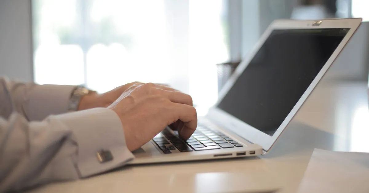Mãos digitando laptop com gráfico financeiro, mostrando sucesso em refinanciamento de caminhão.