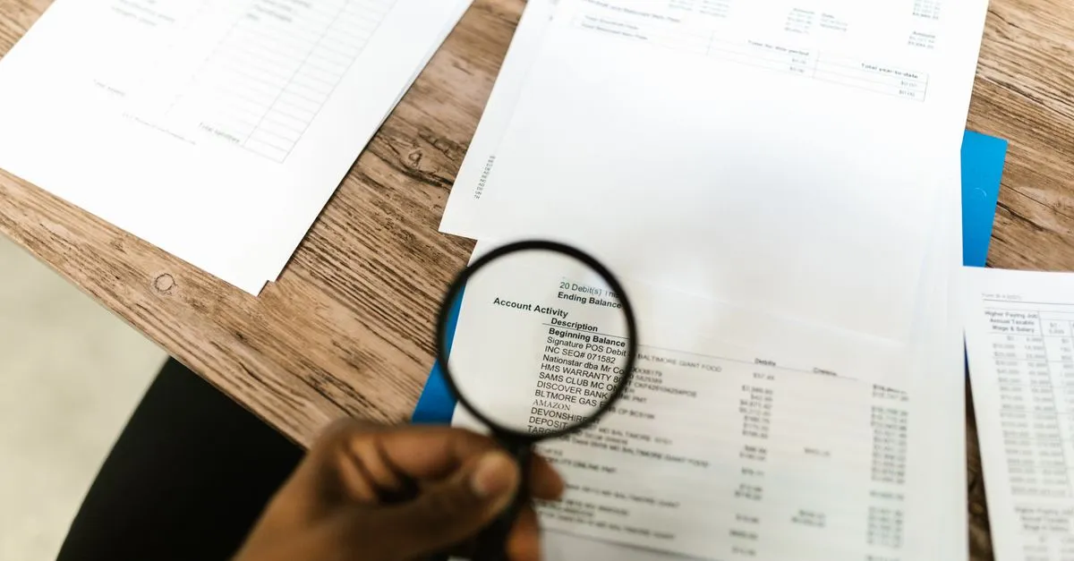 Mão com lupa examina termos de contrato de financiamento de galpão comercial, destacando atenção.
