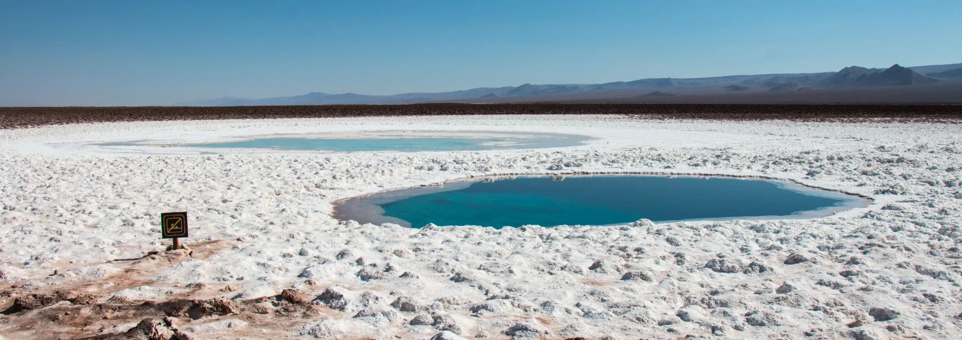 Gêiseres El Tatio ao amanhecer, vapor subindo em paisagem montanhosa. Guia Atacama para tours inesquecíveis.