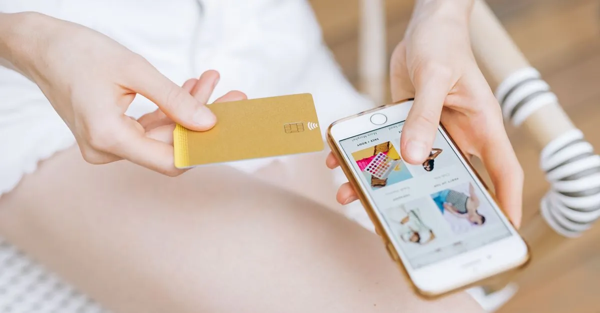 Mãos segurando smartphone com app de indicação, representando o afiliado financeiro para iniciantes.