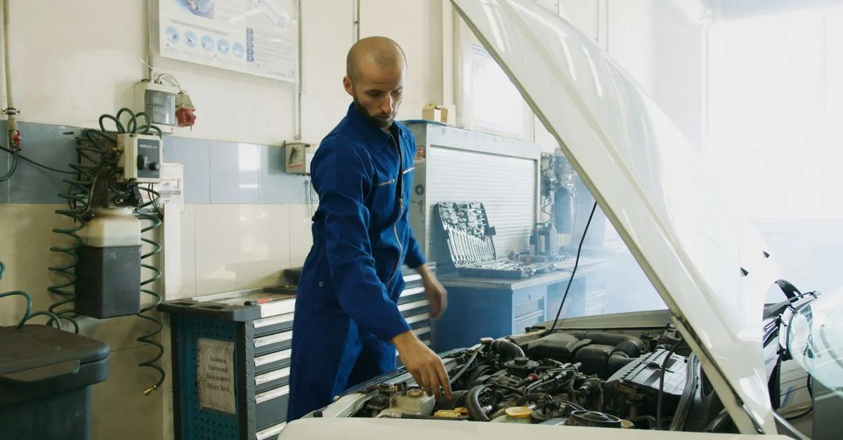 Mecânico inspecionando motor para evitar custos extras ao financiar carro usado.